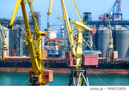 industrial seaport infrastructure, sea, cranes and dry cargo ship, grain silo, bulk carrier vessel and grain storage elevators, concept of sea cargo transportation 94601809