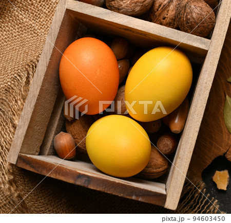 easter holiday still life and decorations, easter eggs in a box with nuts on a dark wooden background 94603450