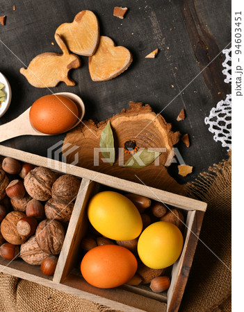 easter holiday still life and decorations, easter eggs, box with nuts on a dark wooden background 94603451