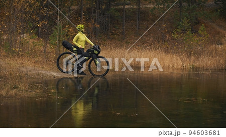 The woman travel on mixed terrain cycle touring with bikepacking. The traveler journey with bicycle bags. Sport tourism bikepacking. 94603681
