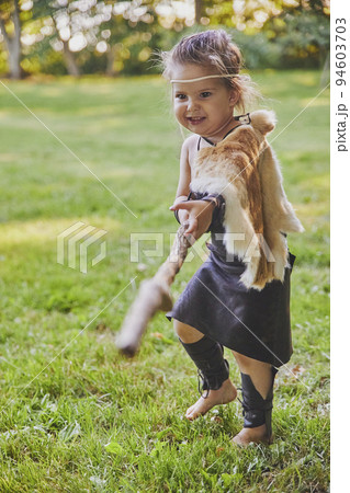 Cute baby dressed in the clothes of primitive people with combat staff 94603703