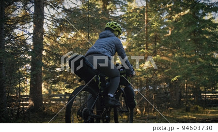 The woman travel on mixed terrain cycle touring with bike bikepacking. The traveler journey with bicycle bags. Magic forest park. 94603730