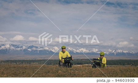 The man and woman travel on mixed terrain cycle touring with bikepacking. The love couple journey with tent in with bicycle bags. Stylish sportswear. 94603930
