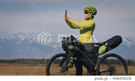 The woman travel on mixed terrain cycle touring with bikepacking. The traveler journey with bicycle bags. Sport tourism bikepacking. The woman travel on mixed terrain cycle touring with bikepacking. The traveler journey with bicycle bags. Sport tourism bikepacking. 94604026