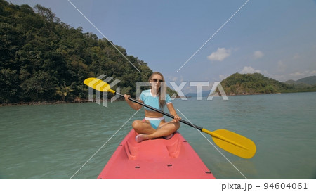 Sportive woman rows pink plastic canoe along sea water. Sportive woman rows pink plastic canoe along sea water. 94604061