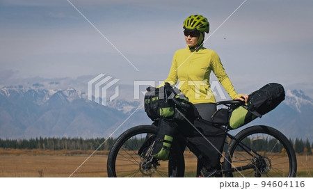 The woman travel on mixed terrain cycle touring with bikepacking. The traveler journey with bicycle bags. Sport tourism bikepacking. The woman travel on mixed terrain cycle touring with bikepacking. The traveler journey with bicycle bags. Sport tourism bikepacking. 94604116