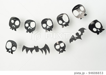 Skulls and flying bats cut out of black paper on a white background, preparation for Halloween. Skulls and flying bats cut out of black paper on a white background, preparation for Halloween. 94606653