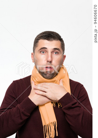 A man suffers from a sore throat, a man wrapped his throat with a scarf, portrait on a white background. A man suffers from a sore throat, a man wrapped his throat with a scarf, portrait on a white background. 94606670
