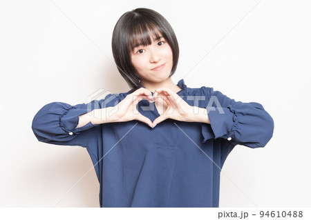手でハートの形を作って、見せている若い女性 94610488