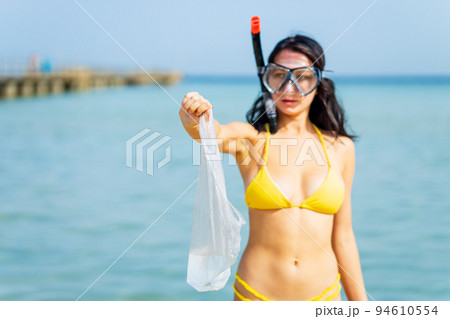 woman in yellow bikini and scuba picking up a plastic trash from sea woman in yellow bikini and scuba picking up a plastic trash from sea 94610554