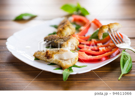 Pieces of fried hake fish in a plate with pepper Pieces of fried hake fish in a plate with pepper 94611066
