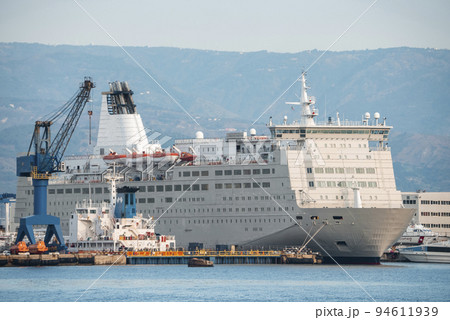 Messina, Sicily, Italy. August 26, 2022. Luxurious cruise ship moored at harbor with mountain in background. Majestic nautical vessel at Mediterranean port in ancient city. 94611939
