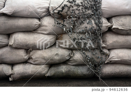 Background of many dirty sand bags for flood defense. Protective sandbag barricade for military use. Handsome tactical bunker Background of many dirty sand bags for flood defense. Protective sandbag barricade for military use. Handsome tactical bunker 94612636