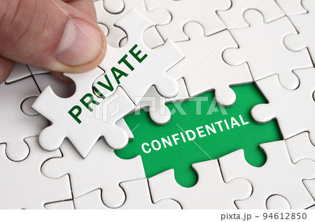 The human hand fills the last missing elements of the surface from the jigsaw puzzle. Image with words private and confidential 94612850