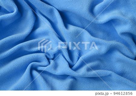 The blanket of furry blue fleece fabric. A background of light blue soft plush fleece material with a lot of relief folds The blanket of furry blue fleece fabric. A background of light blue soft plush fleece material with a lot of relief folds 94612856