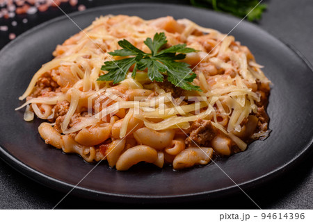 Tasty appetizing classic italian pasta with tomato sauce and cheese on plate on dark background Tasty appetizing classic italian pasta with tomato sauce and cheese on plate on dark background 94614396