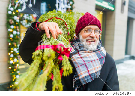 happy retired man walking by street with christmas tree to home from market 94614597