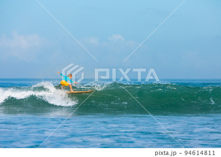 Young surfer learn to ride on surfboard on sea waves 94614811