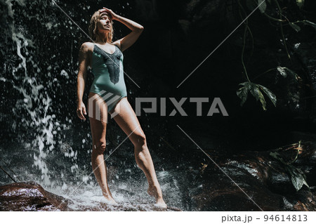 Woman stand on rock under waterfall in tropical jungle 94614813