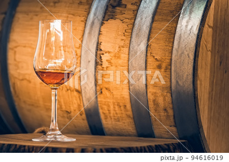 Close up of white port wine in wineglass in front of oak barrel 94616019