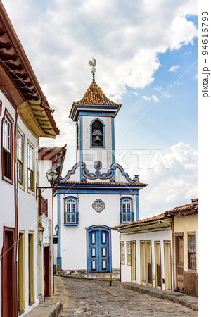 Street with cobblestones and colonial-style houses with a historic church 94616793