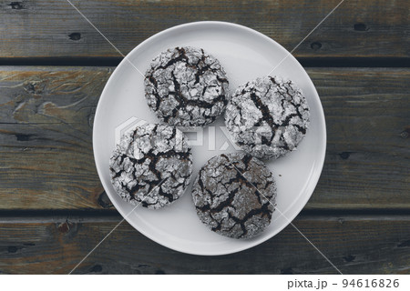 Homemade almond cookies with cocoa sprinkled with powdered sugar on a plate on a wooden background 94616826