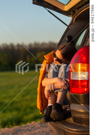 Pretty sad teenage girl with sun glasses sitting alone in a car trunk. Pretty sad teenage girl with sun glasses sitting alone in a car trunk. 94617986