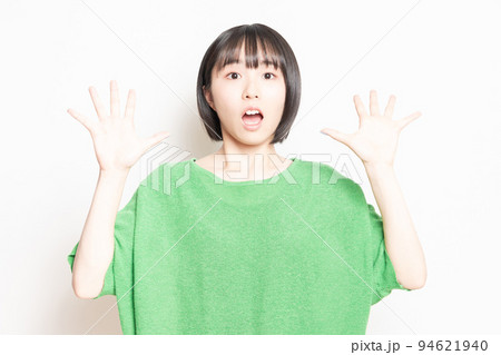 白背景の前で驚いたポーズをする若い女性 94621940