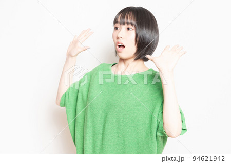 白背景の前で驚いたポーズをする若い女性 94621942