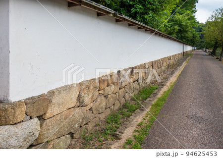 道に沿って続く日本家屋の伝統的な白壁 94625453