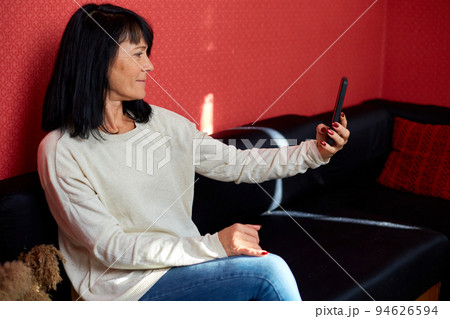 Happy smiling mature woman holding smartphone having video call Happy smiling mature woman holding smartphone having video call 94626594