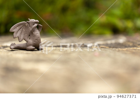 石畳の上に置いてある可愛い素焼のドラゴンの置物 94627371