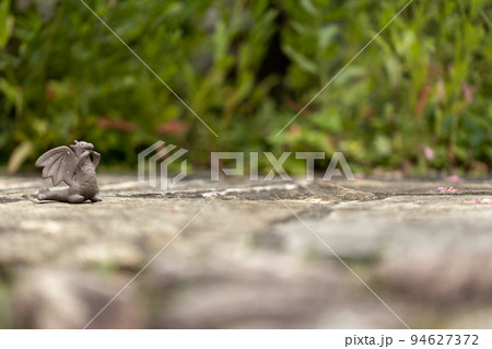 石畳の上に置いてある可愛い素焼のドラゴンの置物 94627372