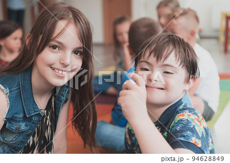 A girl and a boy with Down's syndrome in each other's arms spend time together in a preschool institution A girl and a boy with Down's syndrome in each other's arms spend time together in a preschool institution 94628849