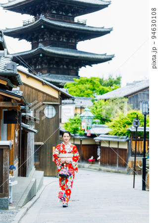 五重塔を背景に立つ着物姿の若い女性 94630108