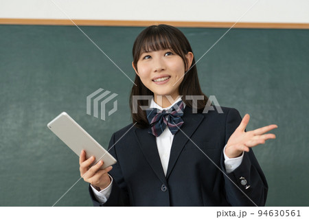 学校の教室でタブレットを手に発表をする女子高生 94630561