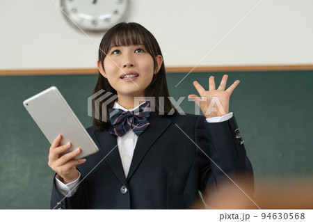 学校の教室でタブレットを手に発表をする女子高生 94630568