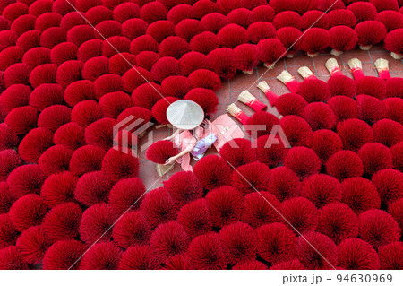 Asian woman wearing ao dai dress with Incense sticks drying outdoor in Hanoi, Vietnam. 94630969