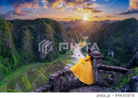 Woman tourist sitting on Hang Mua viewpoint. Popular tourist attraction at Tam Coc, Ninh Binh. Vietnam. 94630978