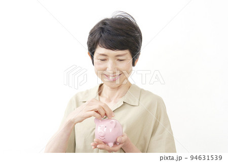 豚の貯金箱に貯金する中年女性 白背景 豚の貯金箱に貯金する中年女性 白背景 94631539