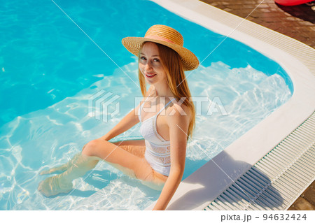 a woman in a white swimsuit in a straw hat in the pool. 94632424