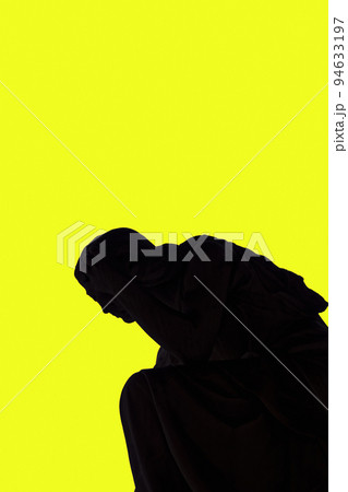 Statue shadow silhouette of an angel against a yellow background. 94633197