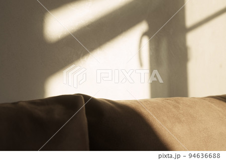 indoor shot of a couch with window frame shadow on it and on the wall behind it indoor shot of a couch with window frame shadow on it and on the wall behind it 94636688
