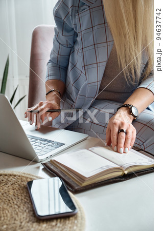 Unrecognizable woman using laptop sitting on chair at home office 94637742