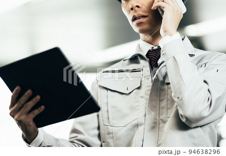 オフィスで電話をする作業服の若い男性 94638296