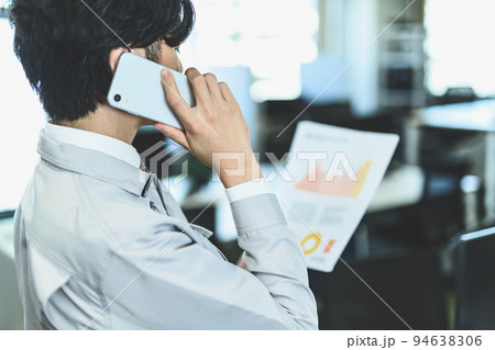 オフィスで電話をする作業服の男性 オフィスで電話をする作業服の男性 94638306