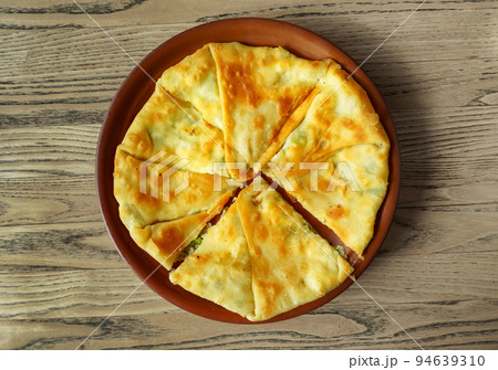 One placinda on a wooden table. Flour products of Moldovan cuisine include various fried pies with stuffing, cottage cheese or potatoes, cabbage, etc. One placinda on a wooden table. Flour products of Moldovan cuisine include various fried pies with stuffing, cottage cheese or potatoes, cabbage, etc. 94639310