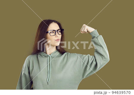 Confident strong young girl flexing her arm and showing her power isolated on brown background 94639570