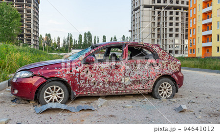 Damaged and destroyed civilian car with shrapnel holes from Russian missile in a war zone in Kharkiv, Ukraine 94641012