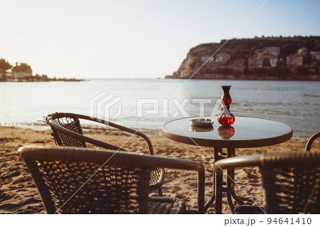 empty cafe table and chairs on sandy beach with ashtray and candle light in front of sea golf 94641410